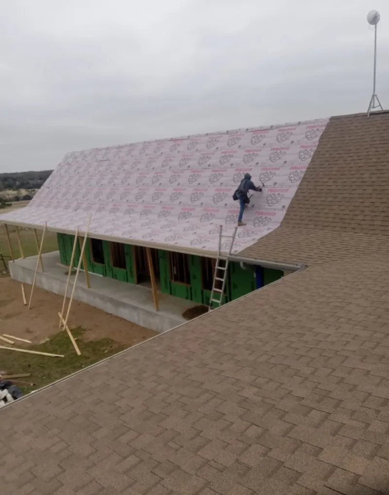 Worker preparing underlayment for a metal roof installation in Russellville